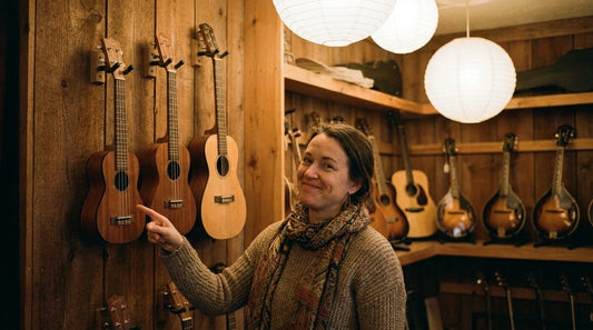 Quatre ukulélés de tailles différentes alignés côte à côte — soprano, concert, ténor, baryton — sur un parquet en bois clair